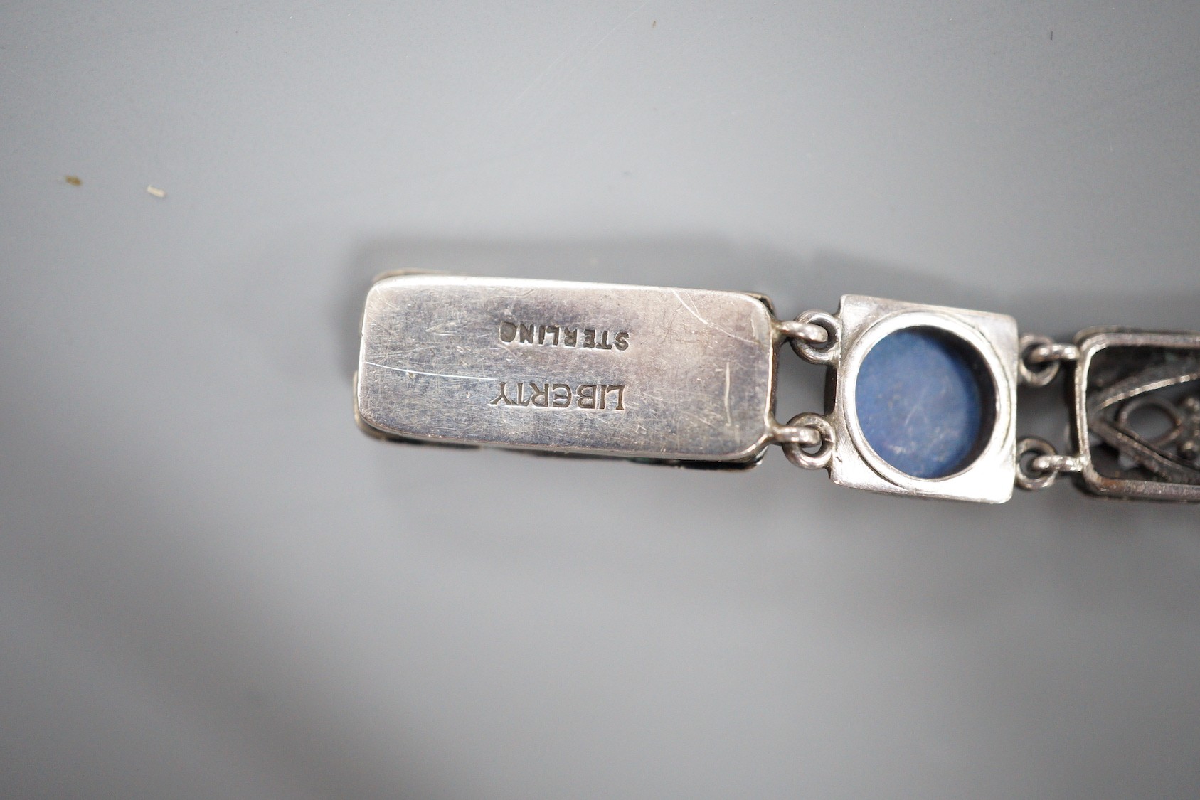 A stylish early 20th century white metal and two colour ten stone lapis lazuli?? or possibly enamel?? cabochon set bracelet, stamped 'Liberty Sterling', 18.3cm.